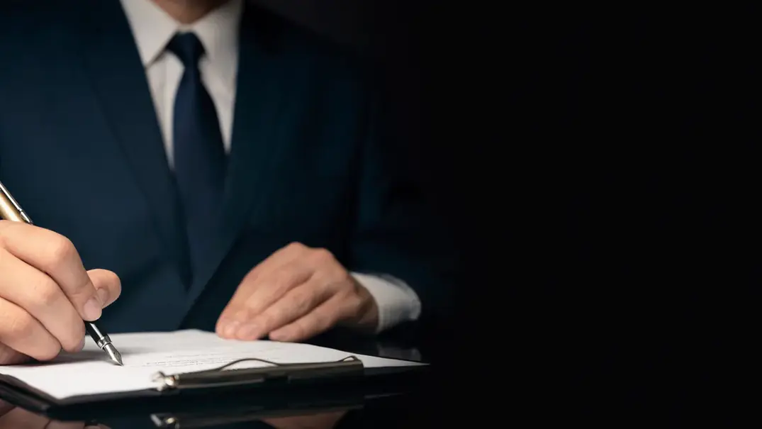 Advogado de terno tomando notas em caderno sobre mesa escura