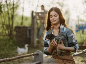 Mulher segurando filhote no colo em área rural